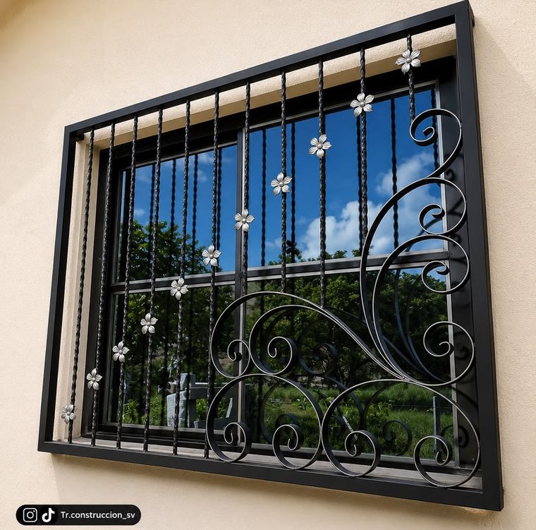 Balcón metálico de ventana con forja de volutas y flores en acero