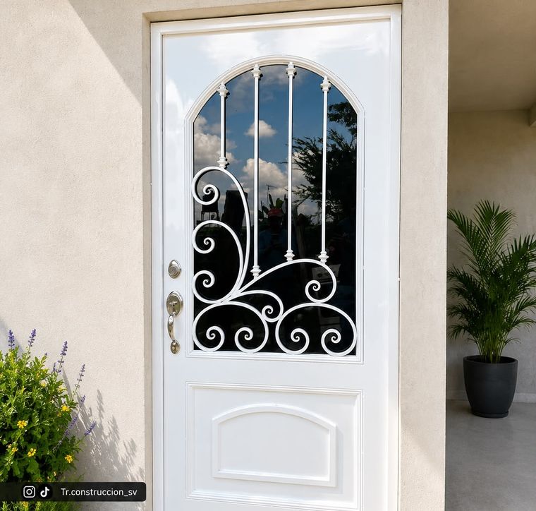 Puerta blanca con remate en medio punto, forja decorativa de volutas y vidrio de seguridad
